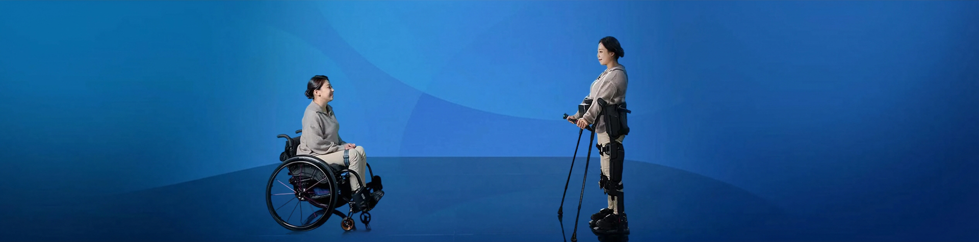 A woman in a wheelchair faces another wearing Hyundai’s X-ble MEX exoskeleton