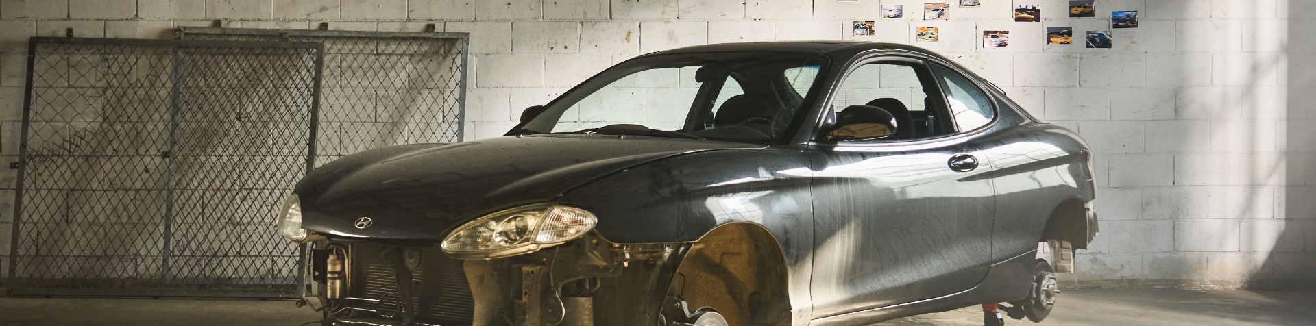 The unfinished chassis of a Hyundai Tiburon in a garage awaiting restoration