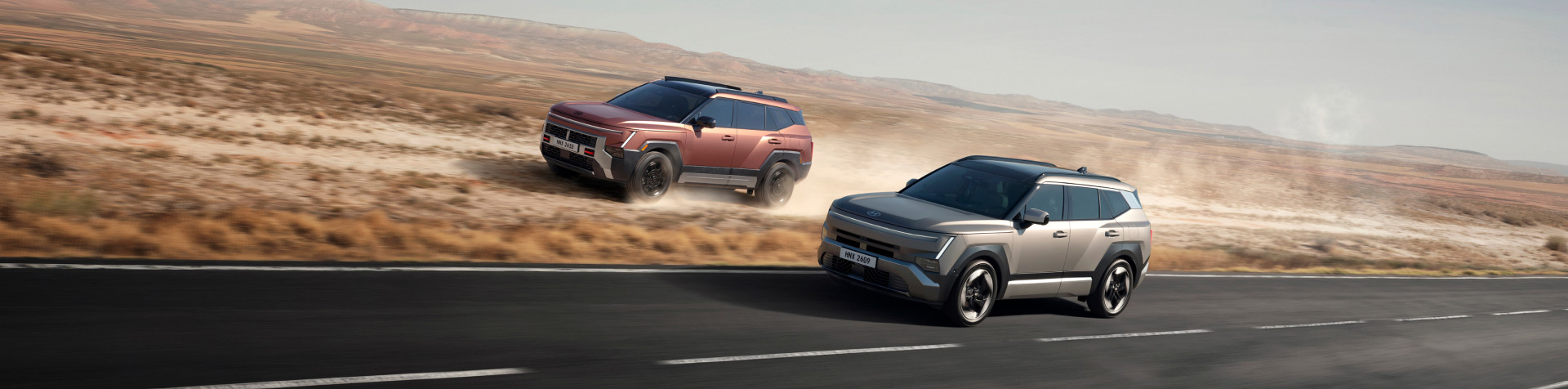 Two all-new Hyundai TUCSON models driving side by side, one on an open road and the other across dusty off-road terrain.