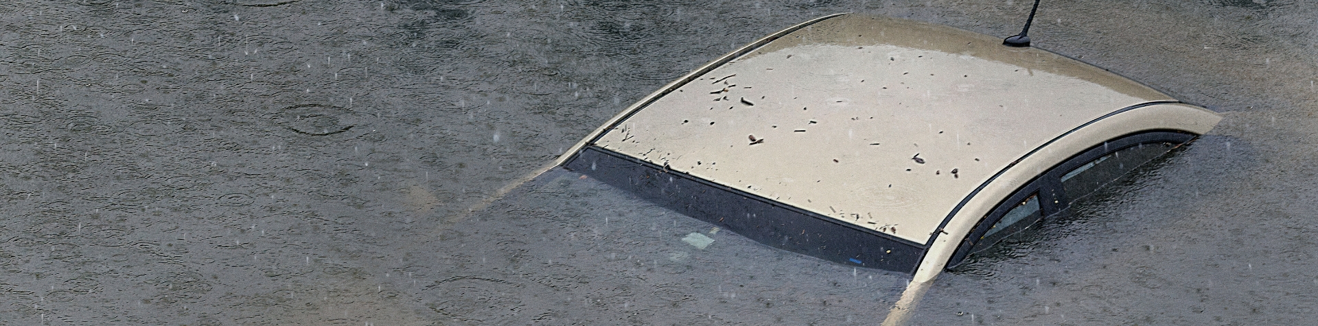 A car lies almost submerged underwater due to a storm.