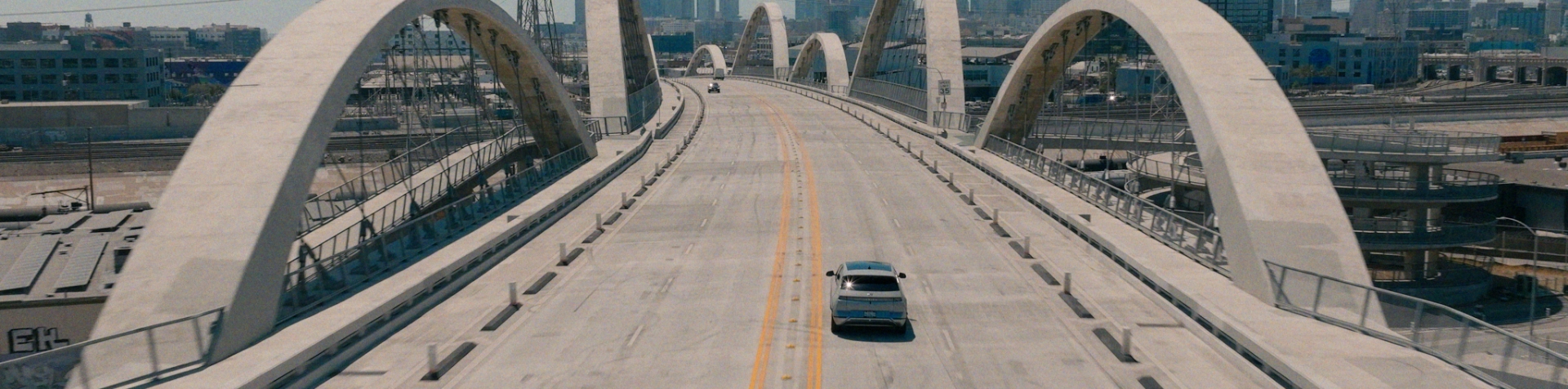 A Hyundai IONIQ 6 crosses over a bridge in LA on a sunny day