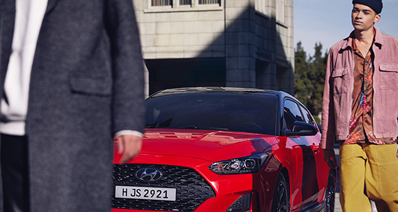 Left side front view of red veloster parking on the road