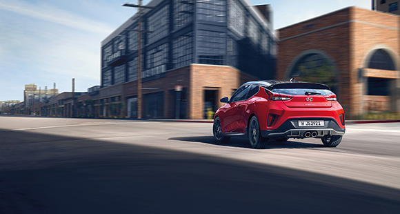 Left side view of red veloster driving on the road