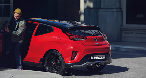 Left side rear view of red veloster parking on the road