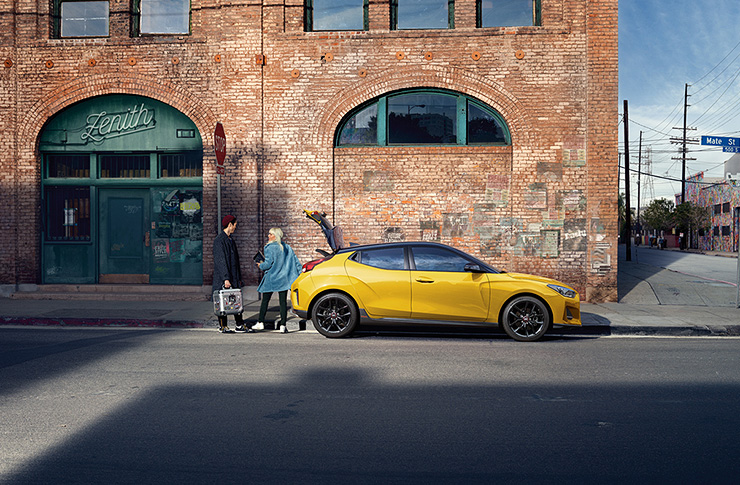 Right side view of red Veloster that opened trunk parked on the road.