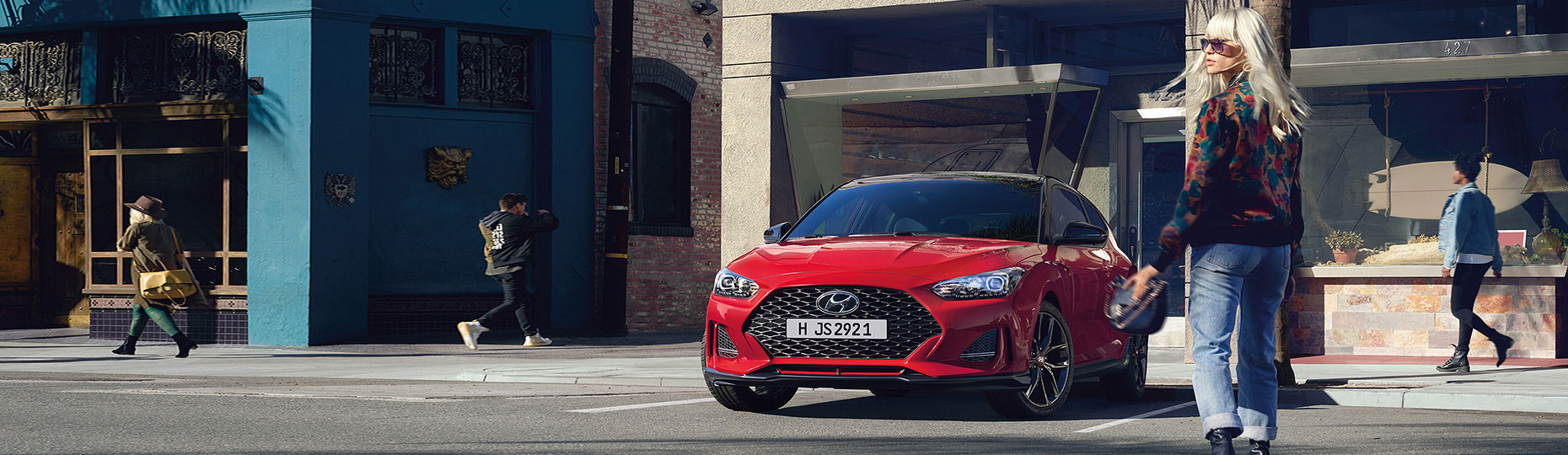 Red Veloster parked on the road beside blond woman