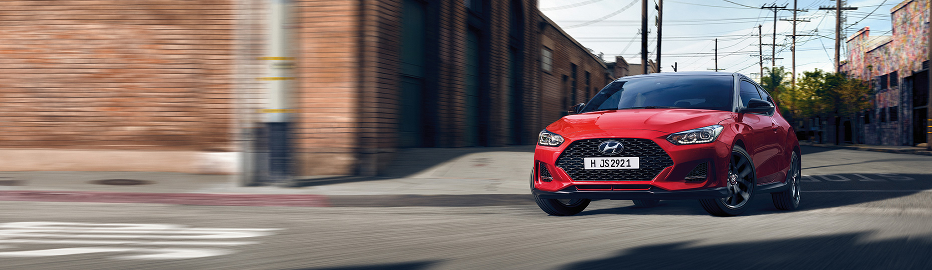 Blue color Veloster is placed in front of a modern building