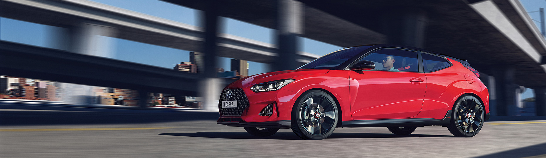 Blue color Veloster is placed in front of a modern building