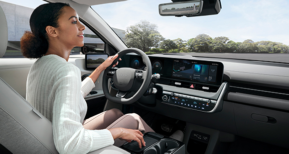 The woman is looking in the rearview mirror while holding the steering wheel