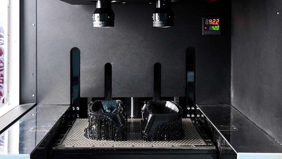 A vat photopolymerization process fabricates a component by curing liquid resin layer by layer using light